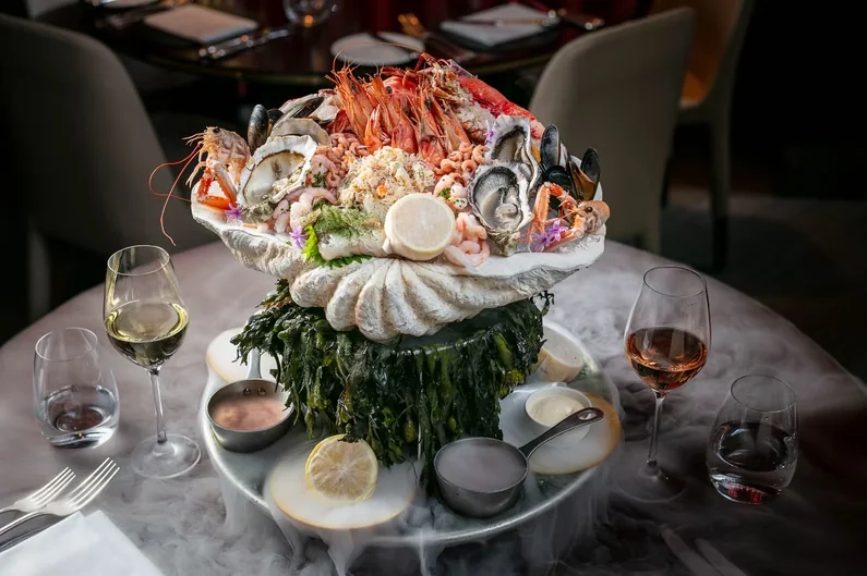 A seafood stand with shellfish, lemon and glasses on a table