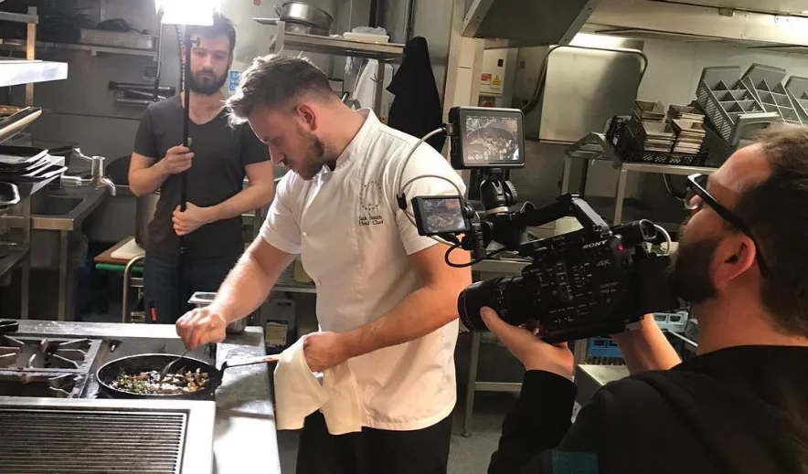 A camera crew filming Jack Smith in a working kitchen